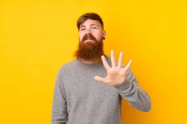 Kızıl saçlı, uzun sakallı, izole edilmiş sarı arka planı olan beş parmaklı bir adam.