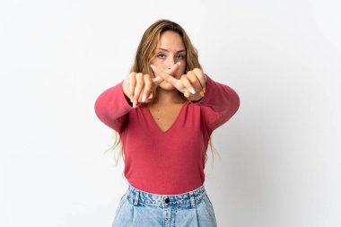 Mavi arka planda izole edilmiş genç sarışın kadın bir hareketi durdurmak için eliyle hareket yapıyor.