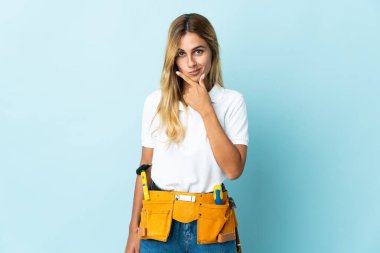 Genç sarışın Uruguaylı elektrikçi kadın mavi arka planda izole edilmiş.