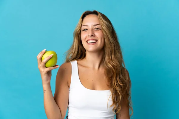 一个年轻的金发女人 带着一个苹果和一个快乐的蓝色背景 — 图库照片