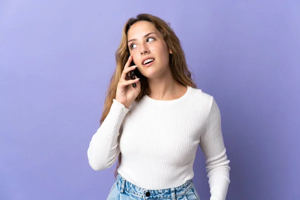 Młoda Blondynka Odizolowana Fioletowym Tle Rozmawiająca Kimś Przez Telefon Komórkowy — Zdjęcie stockowe