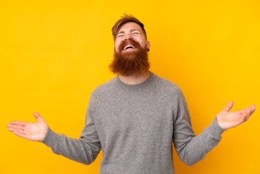 Kızıl saçlı, uzun sakallı, izole edilmiş sarı arka planı olan, gülümseyen bir adam.