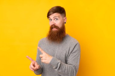 Kızıl saçlı, uzun sakallı, izole edilmiş sarı arka planı olan, korkmuş ve kenarı gösteren bir adam.