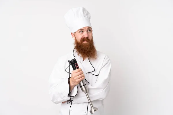 Rödhårig Man Med Handmixer Över Isolerad Vit Bakgrund Tänker Idé — Stockfoto