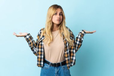 Genç sarışın Uruguaylı, mavi arka planda izole edilmiş şüpheli hareketler yapıyor.