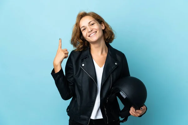 グルジアの女の子を保持していますオートバイのヘルメット隔離された上の青の背景ショーと持ち上げる指で最高の兆候 — ストック写真