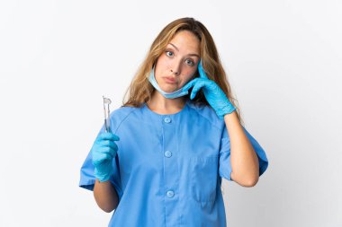 Kadın dişçi beyaz arka planda izole araçlar tutarak bir fikir düşünme