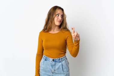 Mavi arka planda izole edilmiş genç sarışın kadın parmaklarını çapraz yapıp en iyisini diliyor.