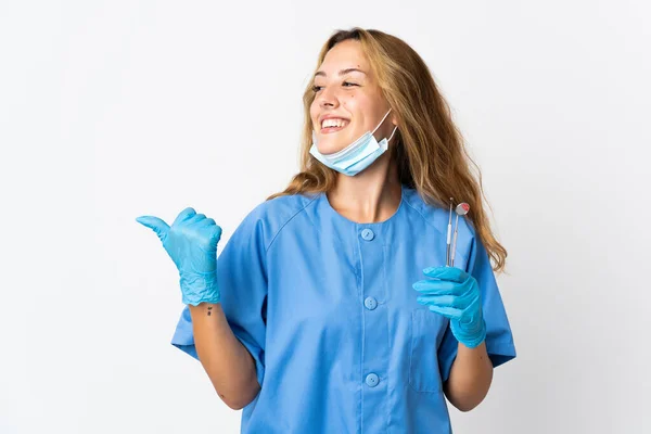 女牙医手持在白色背景下隔离的工具 指向侧面来展示一种产品 — 图库照片