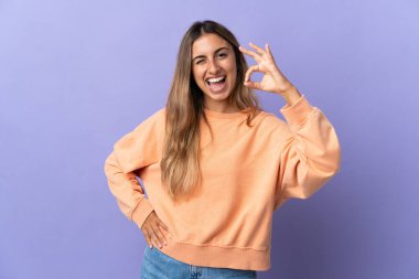 İzole edilmiş mor arka planda genç İspanyol kadın parmaklarıyla işaret veriyor.