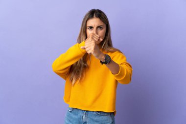 İzole edilmiş mor arka planda dövüşen genç İspanyol kadın.