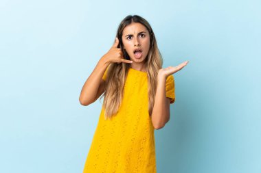 Genç İspanyol kadın izole edilmiş mavi arka planda telefon jesti yapıyor ve şüpheci