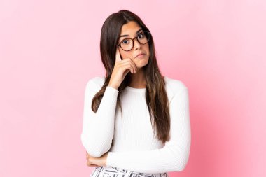 Pembe arka planda izole edilmiş genç Brezilyalı kadın bir fikir düşünüyor.