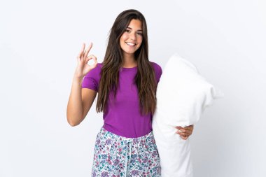 Genç Brezilyalı kız pijamalarıyla beyaz arka planda izole edilmiş ve parmaklarıyla işaret veriyor.