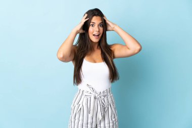 Mavi arka planda mahsur kalmış Brezilyalı genç bir kadın sürpriz bir ifadeyle