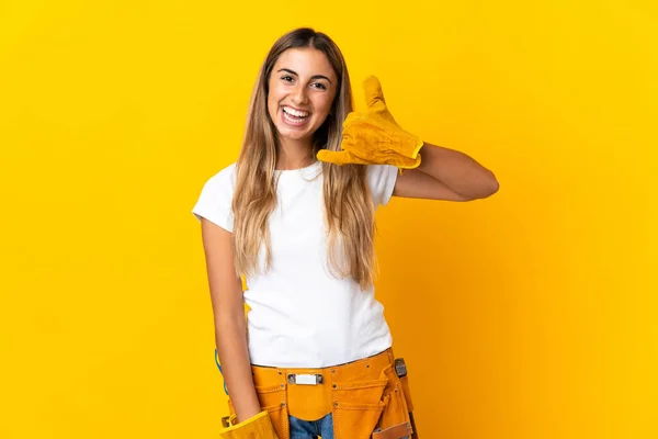 Young hispanic electrician woman over isolated yellow wall making phone gesture. Call me back sign