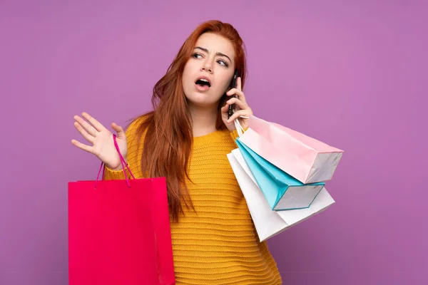 Pelirroja Adolescente Chica Sobre Aislado Púrpura Fondo Sosteniendo Bolsas Compras —  Fotos de Stock