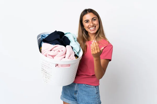 Young woman holding a clothes basket isolated on white background inviting to come with hand. Happy that you came
