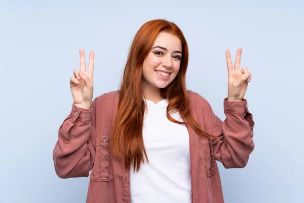 Redhead Teenager Dívka Přes Izolované Modré Pozadí Ukazující Vítězství Znamení — Stock fotografie