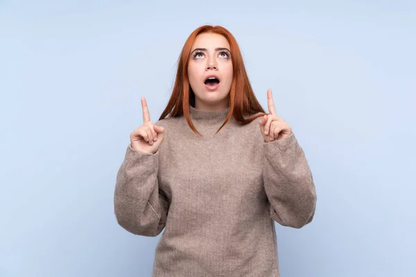 Redhead Teenager Dívka Svetrem Přes Izolované Modré Pozadí Ukazuje Ukazováčkem — Stock fotografie
