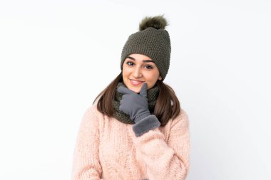 Kışlık şapkalı genç kız soyutlanmış beyaz arka planda gülüyor