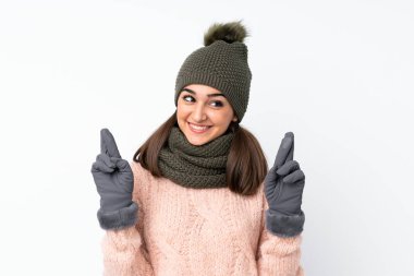 Kışlık şapkalı genç kız izole beyaz arka planda parmakları çapraz