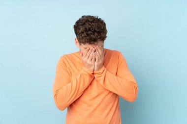 Beyaz adam mavi arka planda izole edilmiş, yorgun ve hasta bir ifadeyle.