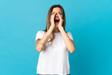 Genç Slovak kadın mavi arka planda izole edilmiş bağırıyor ve bir şeyler söylüyor.