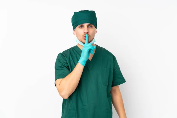 身穿绿色制服的外科医生被隔离在孤立的白色背景中 表现出沉默的姿态 用手指捂住嘴 — 图库照片