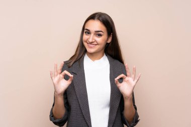 İzole edilmiş arka planda genç bir kız parmaklarıyla iyi bir işaret gösteriyor.