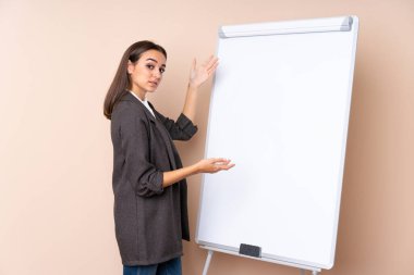 Beyaz tahtada sunum yapan genç bir kadın beyaz tahtada sunum yapıyor.