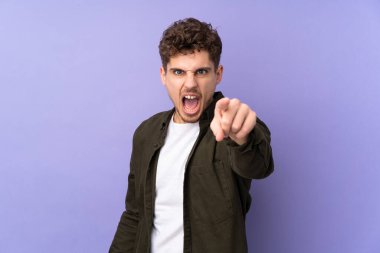 Mor arka planda izole edilmiş beyaz adam hayal kırıklığına uğramış ve ön tarafı işaret ediyor.