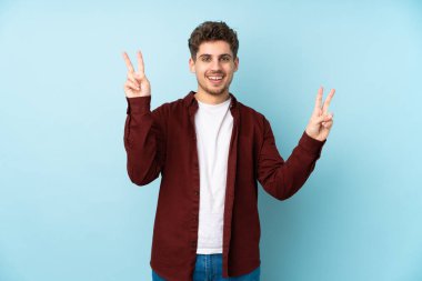 Kafkasyalı genç adam iki eliyle zafer işareti gösteriyor.