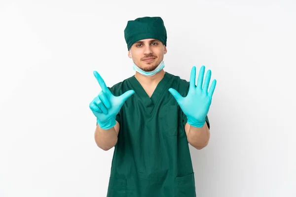 身穿绿色制服的外科医生被隔离在孤立的白色背景上 用手指数着7 — 图库照片