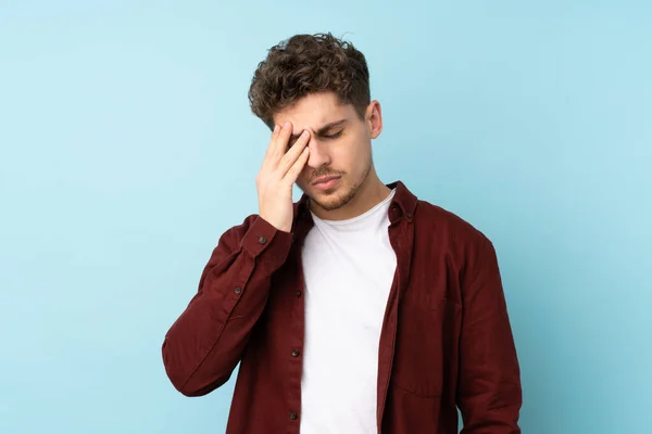 Young caucasian man isolated background with headache
