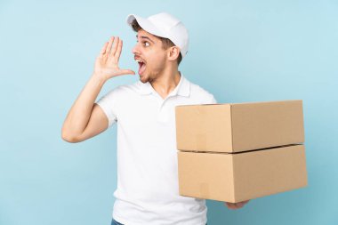Teslimatçı beyaz adam mavi arka planda izole edilmiş ve ağzı açık bağırıyor.