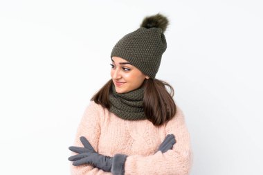 Kışlık şapkalı genç kız izole edilmiş beyaz arka planda yan tarafa bakıyor.