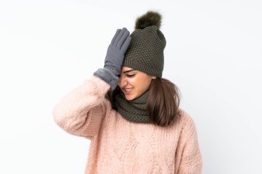 Kışlık şapkalı genç kız izole edilmiş beyaz arka planda, kafası karışık bir yüz ifadesine sahip.