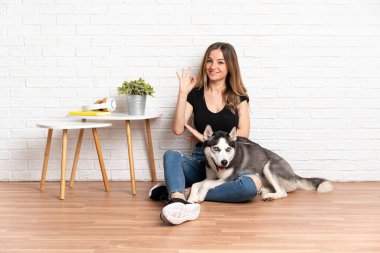İri köpeğiyle yerde oturan genç ve güzel bir kadın parmaklarıyla 