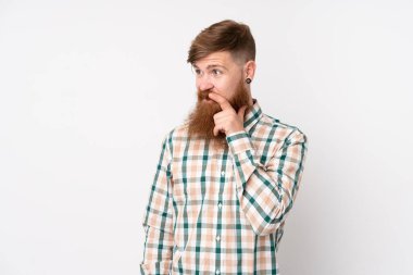 Uzun sakallı, soyutlanmış beyaz arka planda kızıl saçlı adam yan tarafa bakıyor.