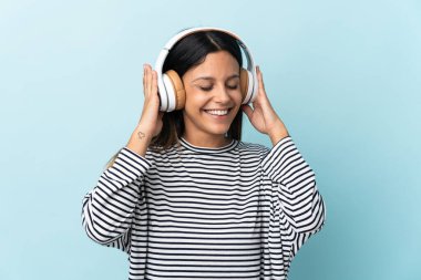 Beyaz kız mavi arka planda izole edilmiş müzik dinliyor.