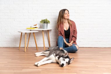 Köpeğiyle yerde oturan genç bir kız. İçeriye bakıyor.