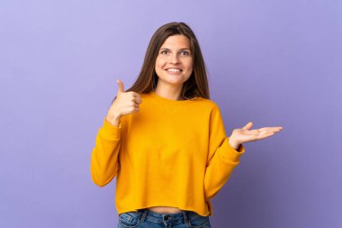 Mor arka planda izole edilmiş genç Slovak kadın bir ilan vermek için avucunun içinde hayali bir mekan tutuyor.