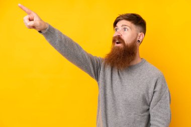 Uzun sakallı, izole edilmiş sarı arka planı olan kızıl saçlı bir adam.