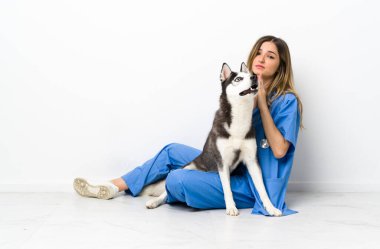 Sibiryalı Husky köpeği olan veteriner doktor yerde oturmuş yalvarıyor.