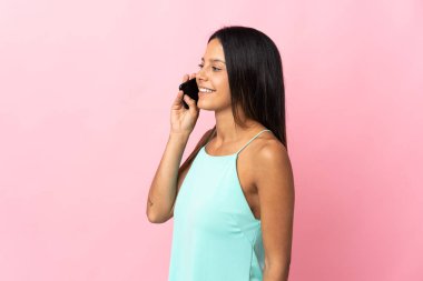 Pembe arka planda izole edilmiş beyaz bir kız cep telefonuyla sohbet ediyor.