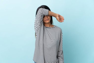 Mavi arka planda izole edilmiş beyaz bir kız gözleri elleriyle kapatıyor.