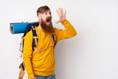 İzole edilmiş beyaz arka plan üzerinde büyük bir sırt çantası olan genç dağcı ağzı açık bağırıyor.