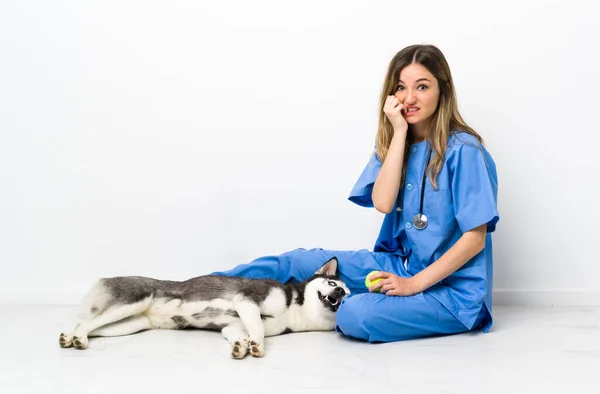 Veterinary doctor with Siberian Husky dog sitting on the floor nervous and scared