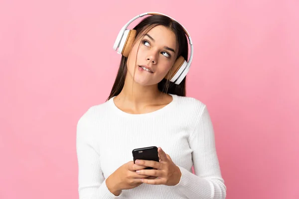 Teenager Girl Isolated Blue Background Listening Music Mobile Thinking — Stock Photo, Image